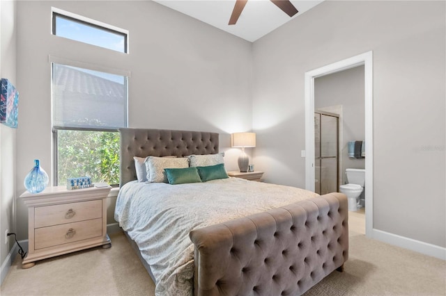 bedroom with baseboards, ensuite bath, a ceiling fan, and light carpet