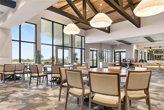 dining room with a high ceiling, a healthy amount of sunlight, and beam ceiling
