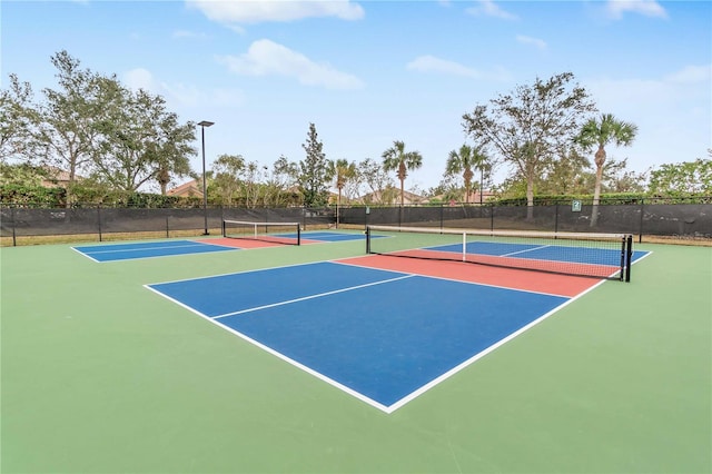 view of tennis court featuring community basketball court and fence
