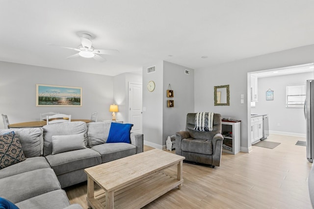living area with a ceiling fan, light wood-style flooring, baseboards, and visible vents