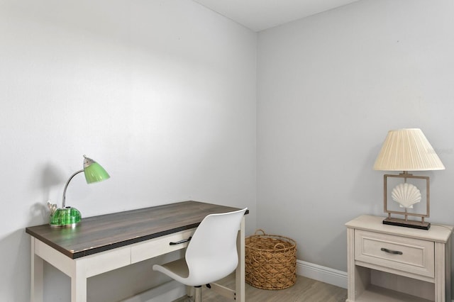 office space featuring built in study area, baseboards, and wood finished floors