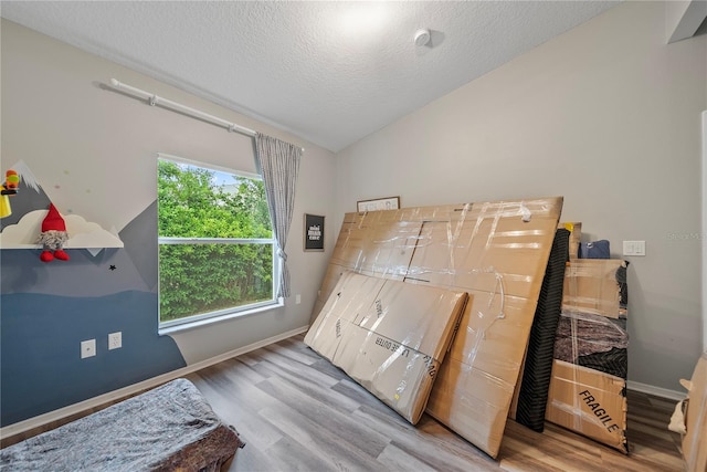 8833 Bel Meadow Way, Trinity, FL 34655 - bedroom featuring a textured ceiling, baseboards, wood finished floors, and lofted ceiling