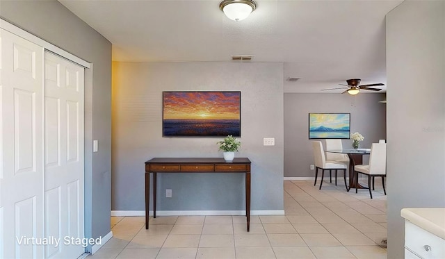 hallway with light tile patterned floors, visible vents, and baseboards