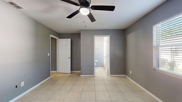 unfurnished bedroom with light tile patterned floors, visible vents, multiple windows, and baseboards