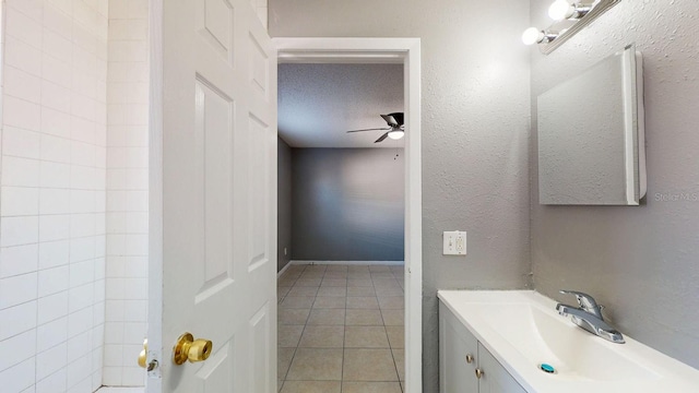bathroom with tile patterned floors, a ceiling fan, a textured ceiling, vanity, and a textured wall
