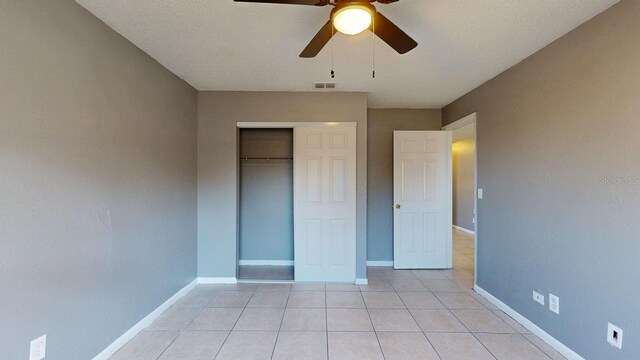 unfurnished bedroom with visible vents, baseboards, light tile patterned floors, a closet, and a ceiling fan