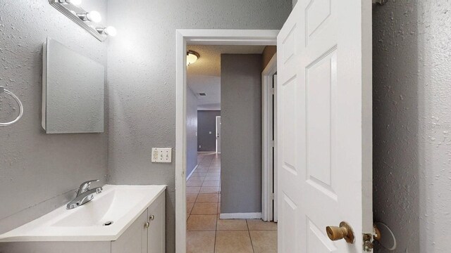 bathroom featuring tile patterned floors, vanity, and a textured wall