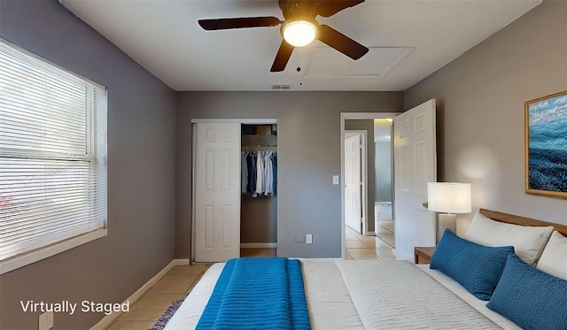 bedroom featuring a ceiling fan, light tile patterned floors, baseboards, and a closet