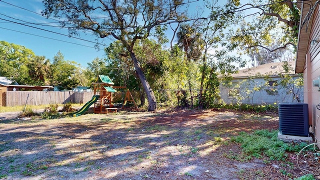 view of yard with central AC unit, a fenced backyard, and a playground