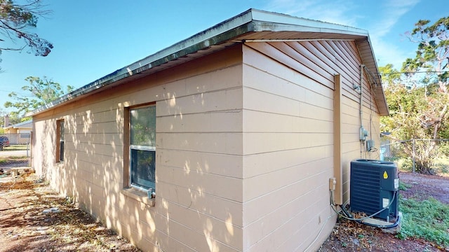 view of side of property with central air condition unit and fence