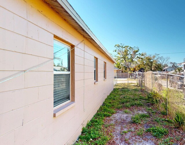 view of property exterior with concrete block siding and fence