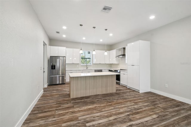 4559 Mitcher Rd, New Port Richey, FL 34652 - kitchen with stainless steel appliances, a center island, wall chimney exhaust hood, dark wood-style flooring, and recessed lighting