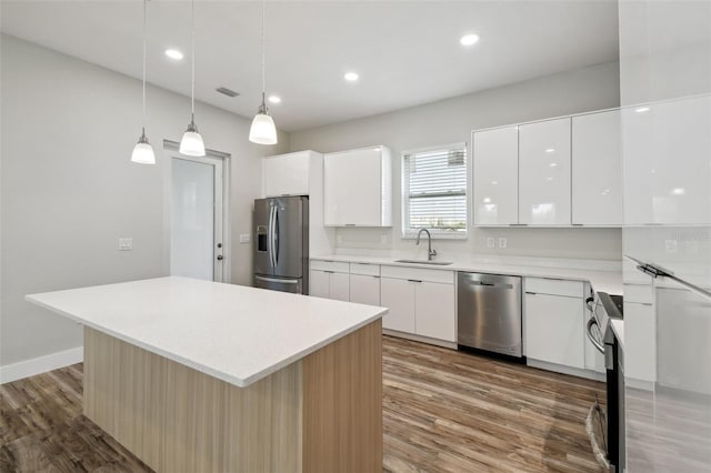 4559 Mitcher Rd, New Port Richey, FL 34652 - kitchen with stainless steel appliances, modern cabinets, wood finished floors, white cabinetry, and recessed lighting