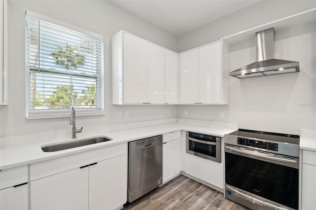 4559 Mitcher Rd, New Port Richey, FL 34652 - kitchen with wall chimney exhaust hood, stainless steel appliances, white cabinets, modern cabinets, and light wood-type flooring
