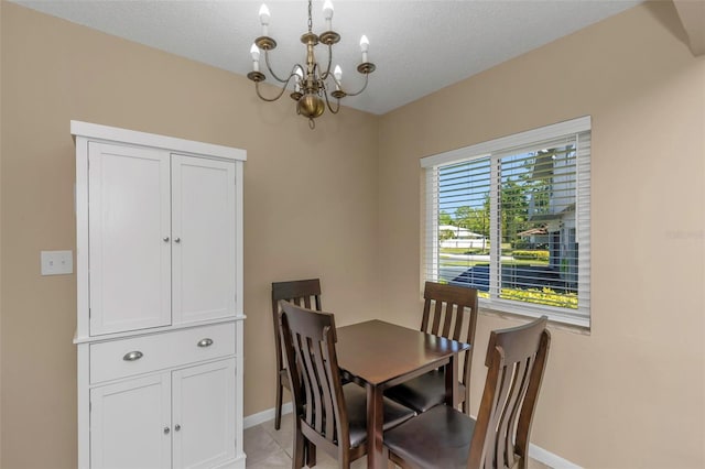 dining space featuring light tile patterned floors, a textured ceiling, a chandelier, and baseboards