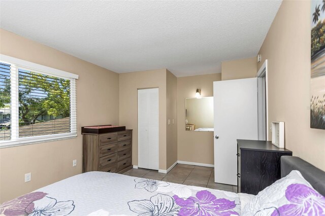 tiled bedroom featuring a textured ceiling, baseboards, and a closet
