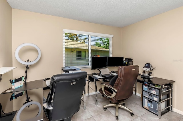 tiled office space featuring a textured ceiling and baseboards