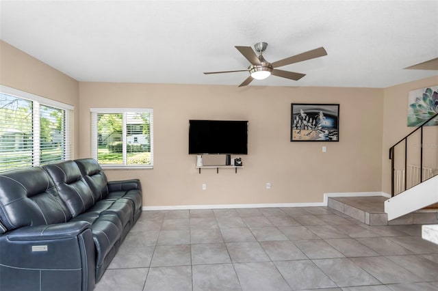 living room featuring baseboards, stairway, light tile patterned floors, and a ceiling fan