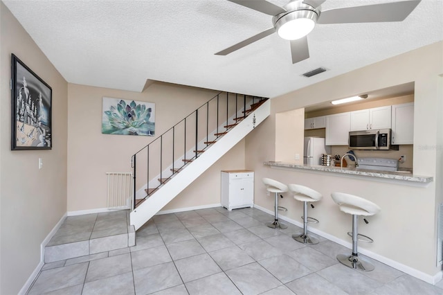 1830 Bough Ave Unit 2, Clearwater, FL 33760 - kitchen featuring stainless steel microwave, freestanding refrigerator, a breakfast bar area, ceiling fan, and a textured ceiling