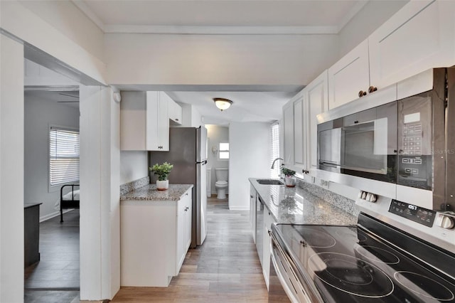 1138 Howard St, Clearwater, FL 33756 - kitchen featuring stainless steel appliances, a sink, light wood finished floors, white cabinets, and light stone countertops
