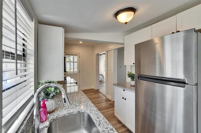 1138 Howard St, Clearwater, FL 33756 - kitchen with light stone counters, a sink, freestanding refrigerator, white cabinetry, and wood finished floors