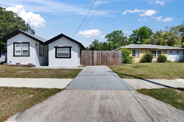 1138 Howard St, Clearwater, FL 33756 - ranch-style home featuring concrete driveway, stucco siding, fence, and a front lawn