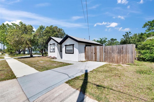 1138 Howard St, Clearwater, FL 33756 - view of front of home with a front lawn, driveway, stucco siding, and fence