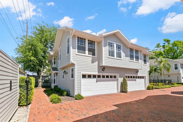 view of front of house featuring a garage, fence, and decorative driveway