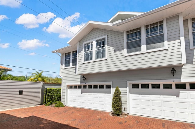 view of property exterior featuring a garage and decorative driveway