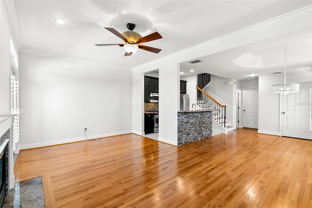 unfurnished living room with visible vents, light wood-type flooring, stairway, and a fireplace with flush hearth