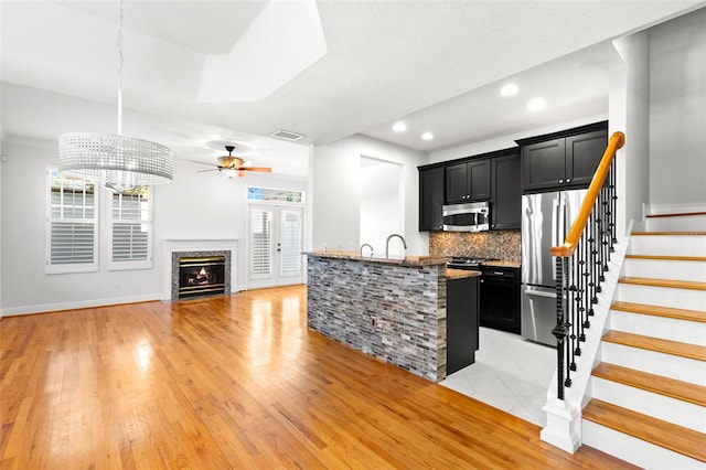 kitchen featuring appliances with stainless steel finishes, visible vents, backsplash, and dark cabinets