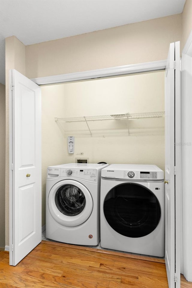 washroom featuring washer and dryer, light wood-type flooring, and laundry area