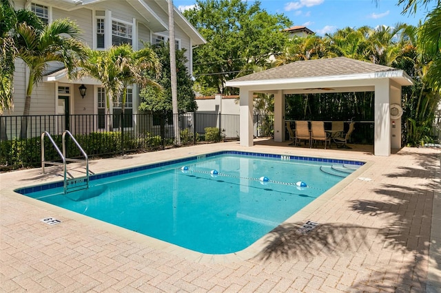 community pool with a patio area, a gazebo, and fence