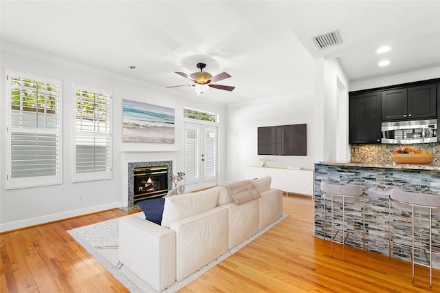 living area with light wood-style floors, plenty of natural light, visible vents, and ceiling fan