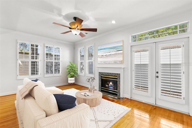 living room featuring wood finished floors, a healthy amount of sunlight, crown molding, and ceiling fan
