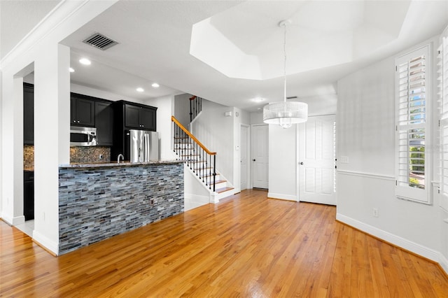 kitchen with visible vents, stainless steel appliances, dark cabinetry, light wood finished floors, and baseboards