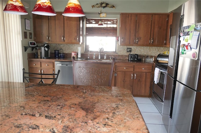 8609 Thimbleberry Ln, Tampa, FL 33635 - kitchen with a sink, stainless steel appliances, decorative backsplash, light tile patterned floors, and brown cabinetry