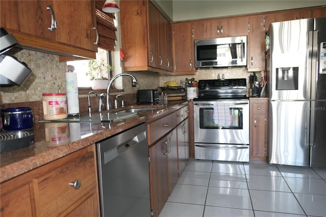8609 Thimbleberry Ln, Tampa, FL 33635 - kitchen with light tile patterned floors, brown cabinets, tasteful backsplash, a sink, and appliances with stainless steel finishes