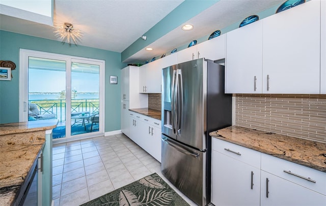 4801 Osprey Dr S Unit 508, Saint Petersburg, FL 33711 - kitchen with light tile patterned flooring, stainless steel fridge with ice dispenser, white cabinetry, light stone countertops, and decorative backsplash
