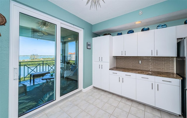 4801 Osprey Dr S Unit 508, Saint Petersburg, FL 33711 - kitchen featuring white cabinetry, light tile patterned floors, decorative backsplash, dark stone counters, and freestanding refrigerator