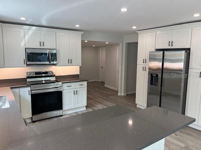 kitchen featuring white cabinets, appliances with stainless steel finishes, light wood-style floors, and recessed lighting