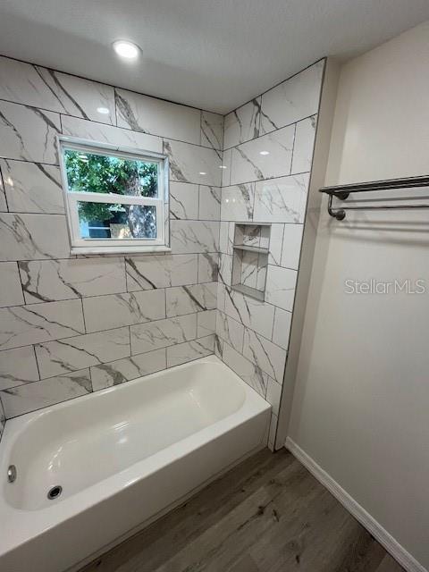 bathroom with shower / bathing tub combination, baseboards, and wood finished floors