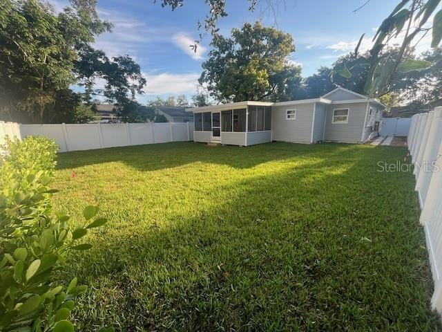 view of yard featuring a fenced backyard and a sunroom