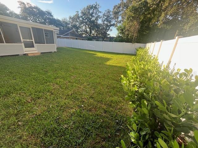 view of yard with a fenced backyard and a sunroom