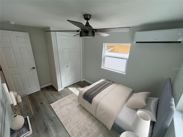 1574 Ewing Ave, Clearwater, FL 33756 - bedroom featuring a wall mounted AC, wood finished floors, a closet, a ceiling fan, and baseboards