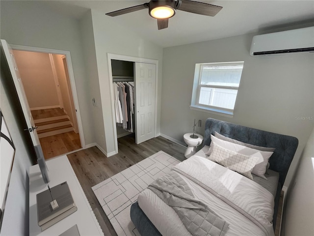 1574 Ewing Ave, Clearwater, FL 33756 - bedroom featuring a wall unit AC, dark wood-style floors, a closet, baseboards, and a ceiling fan
