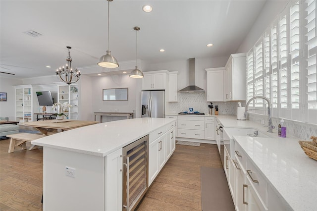 16306 1st St E, Redington Beach, FL 33708 - kitchen with wood finished floors, wall chimney exhaust hood, wine cooler, and appliances with stainless steel finishes