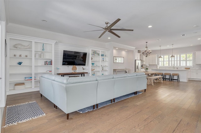 16306 1st St E, Redington Beach, FL 33708 - living area with ornamental molding, wood finished floors, recessed lighting, and ceiling fan with notable chandelier