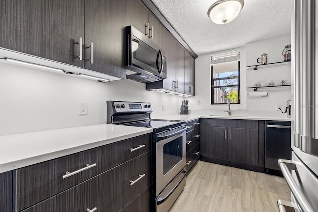 1998 Blue Hawk Ct Unit 1613, Clearwater, FL 33762 - kitchen featuring appliances with stainless steel finishes, a sink, light wood finished floors, a textured ceiling, and light countertops