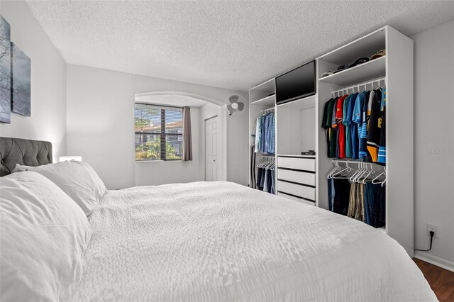 1998 Blue Hawk Ct Unit 1613, Clearwater, FL 33762 - bedroom featuring dark wood finished floors, a textured ceiling, arched walkways, and baseboards